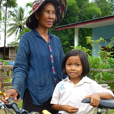 Une vieille dame et une jeune fille accoudée à un vélo au coeur d'un village philippin